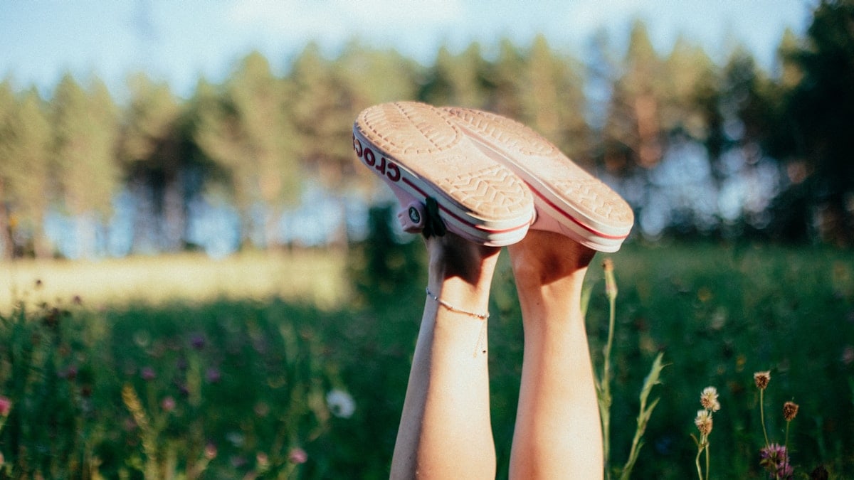 Legs in the air, wearing shoes in a field.