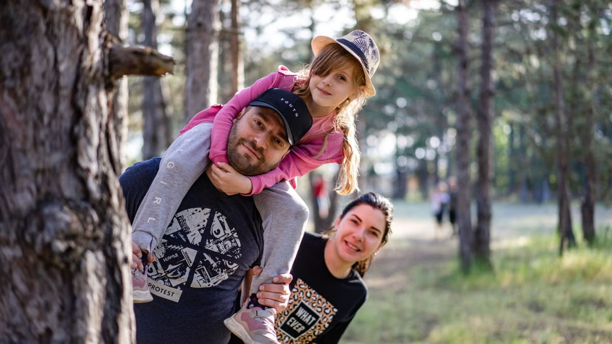 A joyful family enjoying a playful day in a sunlit forest park, capturing the essence of togetherness.